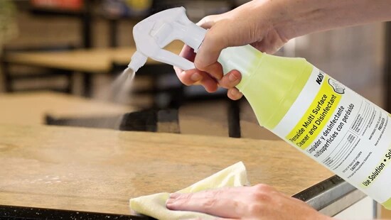 food service worker cleaning table with peroxide multisurface