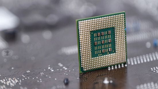 Semiconductor manufacturing stock photo, An old computer processor stands on background of motherboard